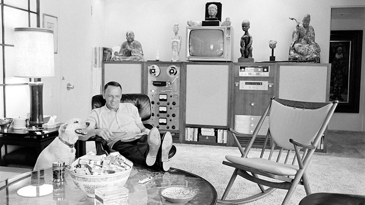 American entertainer Frank Sinatra (1915 - 1998) reads in his living room as his dog, Ringo, sits beside him, Palm Springs, California, 1965.