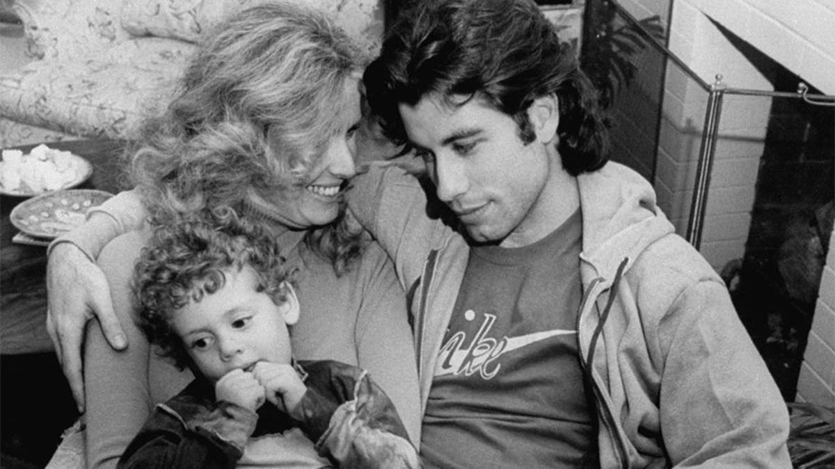 Actor John Travolta w. his arm around actress girlfriend Diana Hyland and her young son Zachary, 4, while sitting together at home.