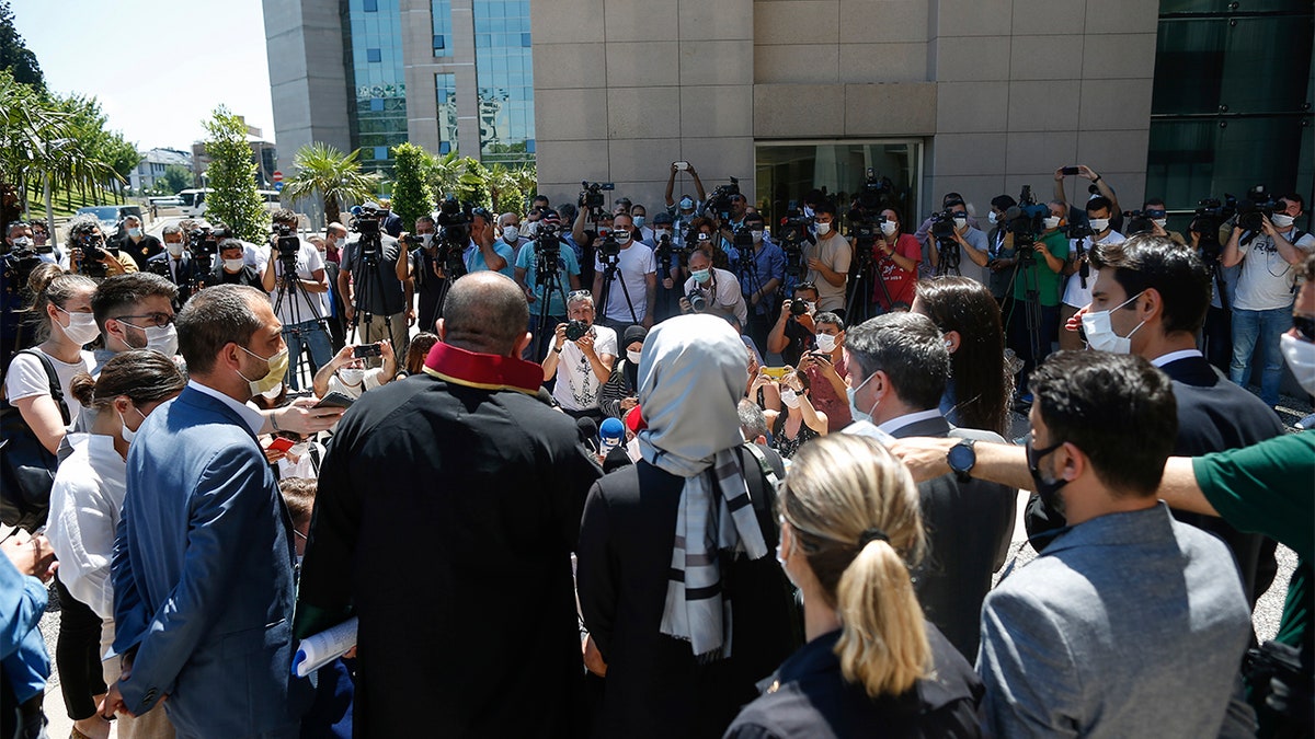 Hatice Cengiz, centre back to camera, the fiancee of slain Saudi journalist Jamal Kashoggi, talks to members of the media outside a court in Istanbul, Friday, July 3, 2020.