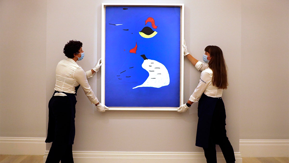 In this Thursday, July 23, 2020 file photo, Sotheby employees adjust a painting by Joan Miro called 'Peinture (Femme au chapeau rouge) at Sotheby's auction rooms in London. Miró’s “Peinture (Femme au chapeau rouge)” (Woman in a Red Hat) from 1927. (AP Photo/Kirsty Wigglesworth, File)