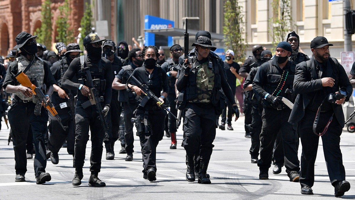 Armed members of the "NFAC" march through downtown Louisville, Ky., toward the Hall of Justice on Saturday. Hundreds of activists demanded justice for Breonna Taylor during the demonstrations in her hometown that drew counter-protesters from a white militia group. (AP Photo/Timothy D. Easley)
