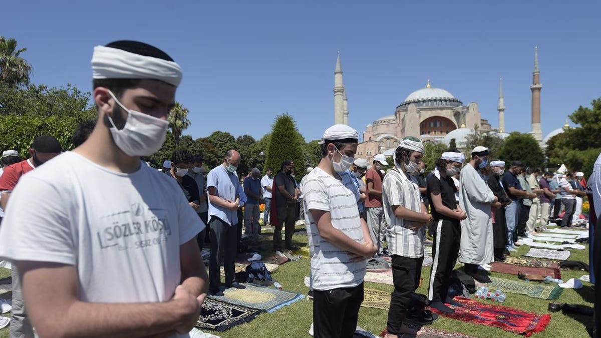 Muslims pray during Friday prayers at the historic Sultanahmet district of Istanbul, near the Byzantine-era Hagia Sophia, background, Friday, July 24, 2020.