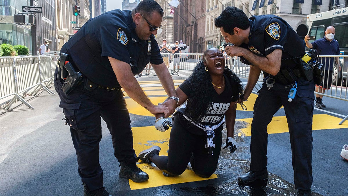 New York Police Department officers attempt to detain a protester who they say used black paint to deface the Black Lives Matter mural outside of Trump Tower on Fifth Avenue Saturday. (AP Photo/Yuki Iwamura)