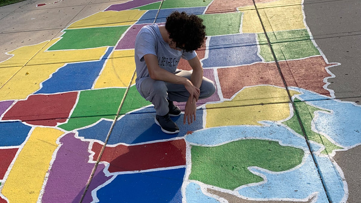 Pastor Edgar Rodriguez’s oldest son prays over Illinois in a street painting of a map of the U.S. in the Logan Square neighborhood in Chicago while on a prayer march.