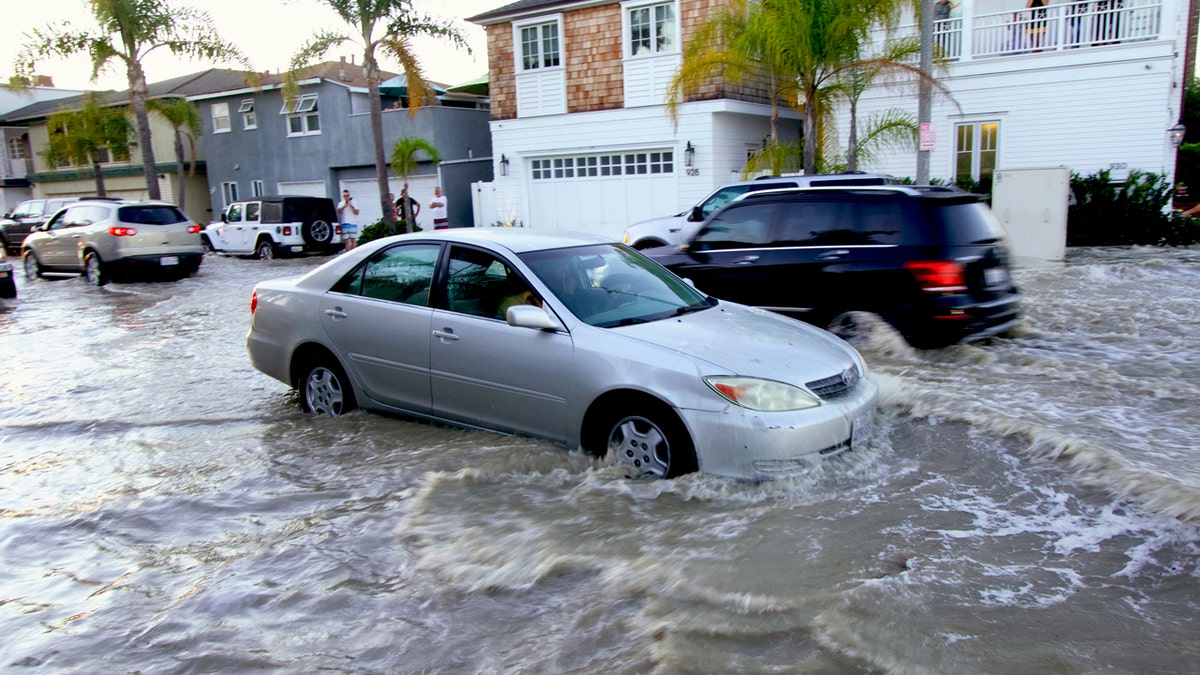 Vehicles drive through flooded streets in Newport Beach, Calif., July 3. The combination of surf and high tides could produce minor coastal flooding at the lowest coastal locations in the evenings during high tide this holiday weekend, according to the National Weather Service.