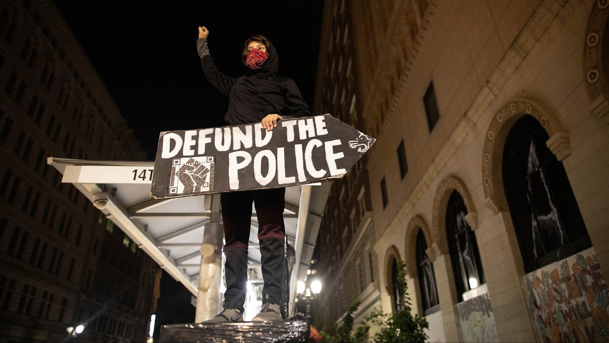 A protester holds a sign calling for the defunding of police at a protest on Saturday, July 25, 2020, in Oakland, Calif. (AP Photo/Christian Monterrosa)