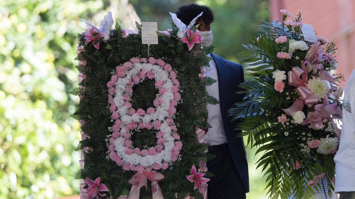 A man carries flowers into a viewing for 8-year-old Secoriea Turner, July 14, 2020, in South Fulton, Ga. (AP Photo/John Bazemore)