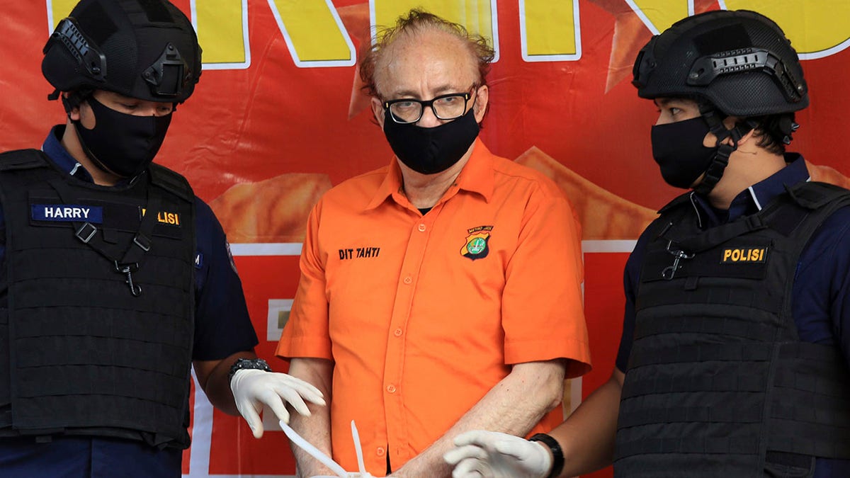 In this Thursday, July 9, 2020, file photo, police officers flank French national Francois Camille Abello, center, as he is presented to the media during a press conference at the regional police headquarters in Jakarta, Indonesia. (AP Photo, File)