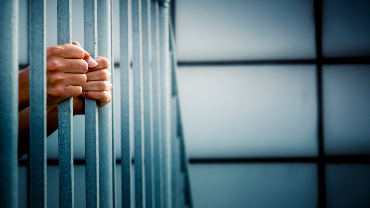Prisionero detrás de las rejas de la celda de la cárcel