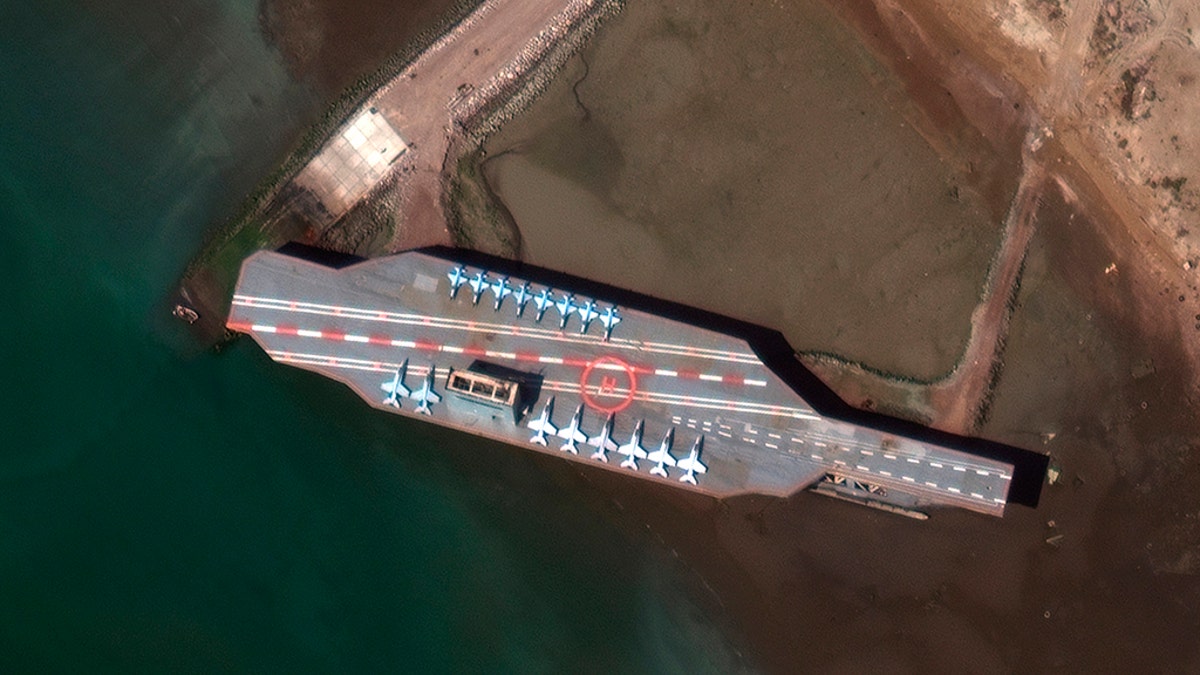 In this Feb. 15, 2020, satellite photo provided on July 27, 2020, by Maxar Technologies, a mockup aircraft carrier built by Iran is seen at Bandar Abbas, Iran, before being put to sea. Satellite photographs released Monday, July 27, showed Iran has moved the aircraft carrier out to sea likely for naval drills amid heightened tensions between Tehran and the U.S. (Maxar Technologies via AP)