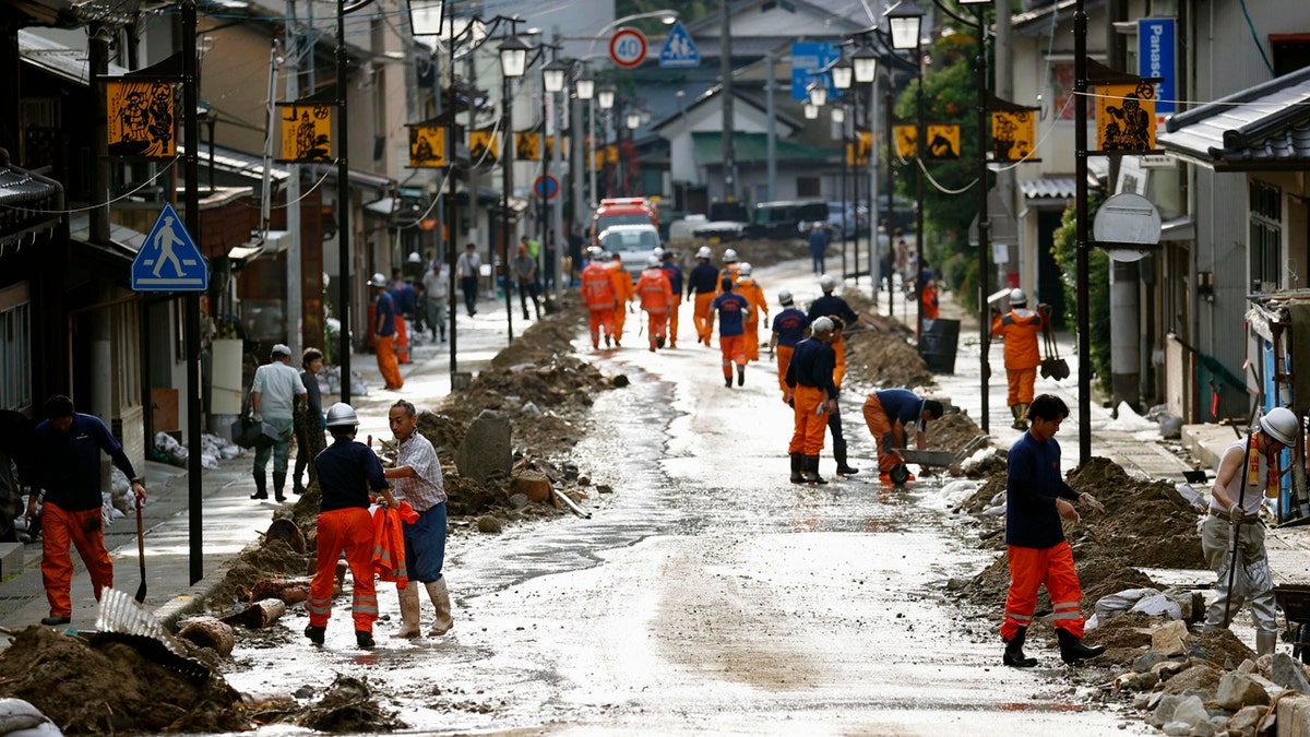 Residents and firefighters put away debris carried by the floodwater in Gero, Gifu prefecture, central Japan Wednesday, July 8, 2020.