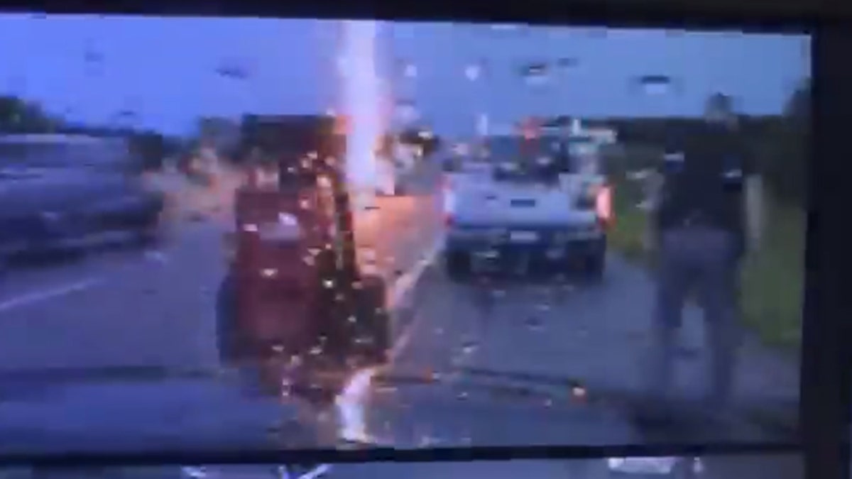Lightning can be seen striking nearby as an Oklahoma Highway Patrol trooper assists a motorist.