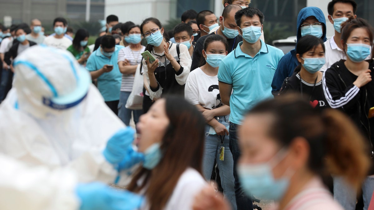 In this Friday, May 15, 2020 file photo, people line up for coronavirus testing at a large factory in Wuhan in central China's Hubei province. In June 2020, China reported using batch testing as part of a recent campaign to test all 11 million residents of Wuhan, the city where the virus first emerged late in late 2019.
