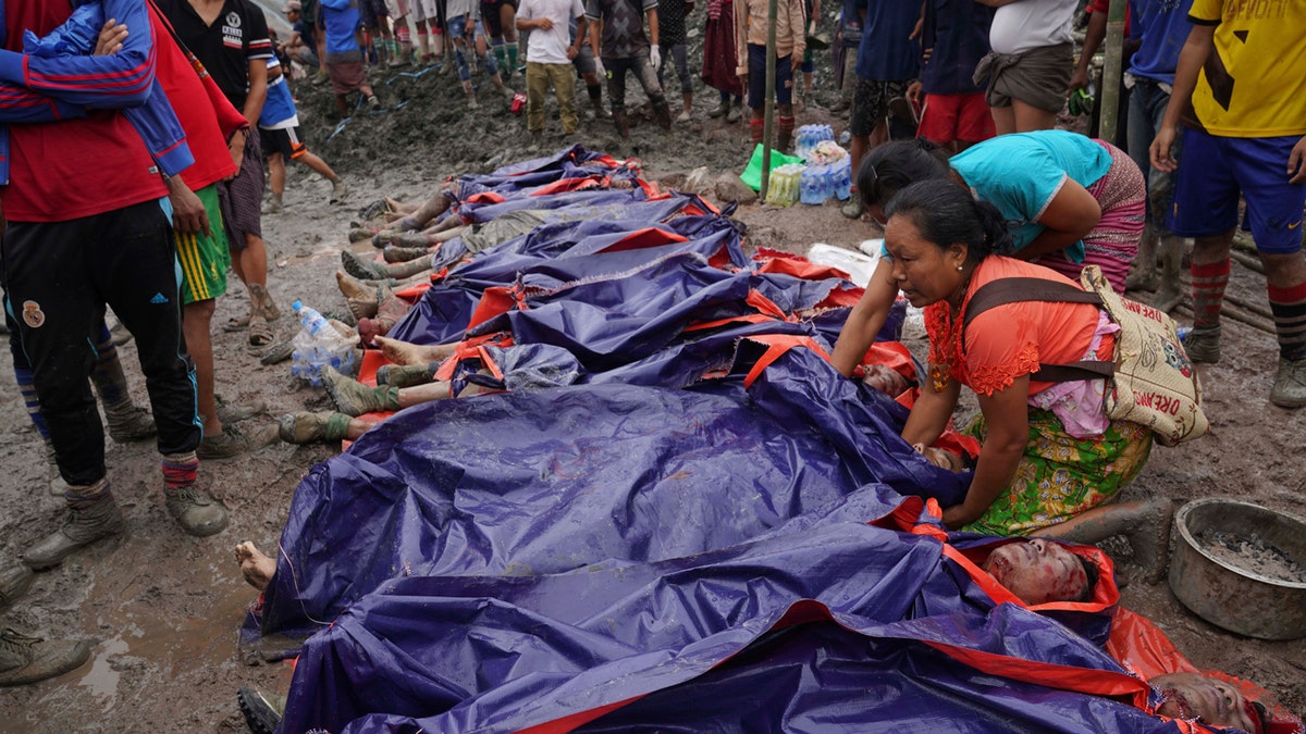 Women look at bodies shrouded in blue and red plastic sheets placed in a row on the ground July 2, in Hpakant, Kachin State, Myanmar.
