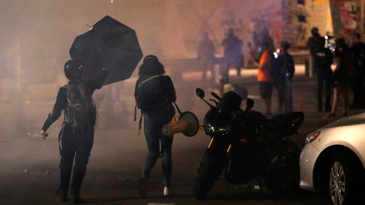 A demonstrator holds an umbrella during a protest against racial inequality in Portland, Oregon, on July 21, 2020. REUTERS/Caitlin Ochs 