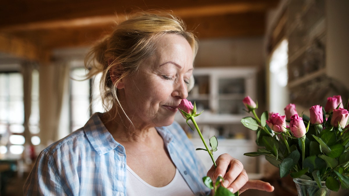 woman at home smelling flower