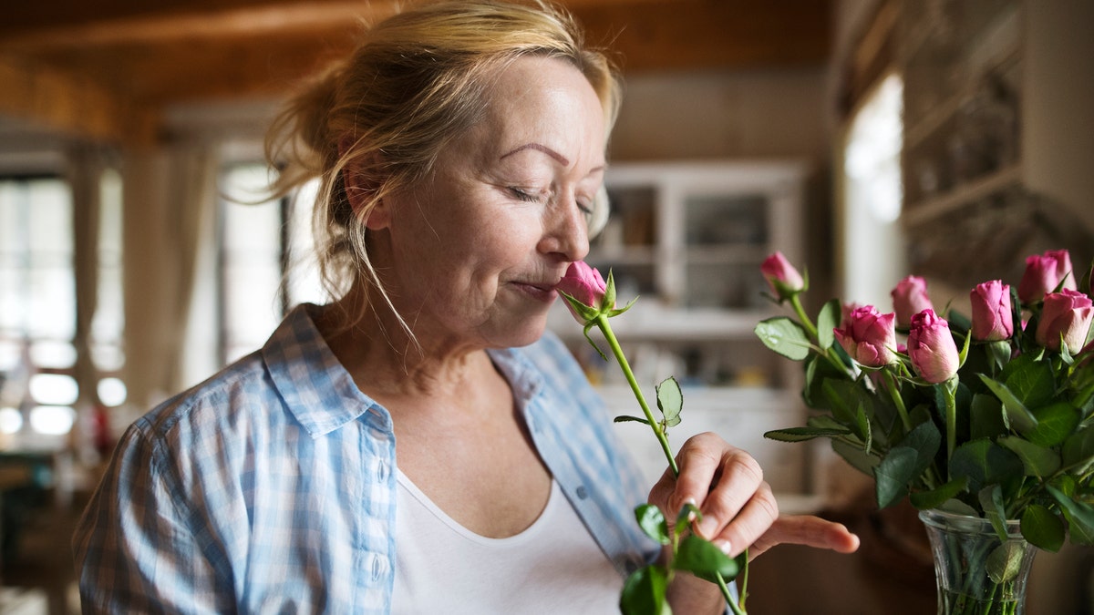 woman at home smelling flower