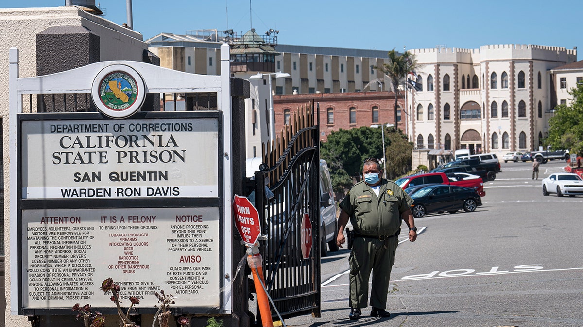 A California Department of Corrections and Rehabilitation (CDCR) officer wearing a protective mask stands at the front gate of San Quentin State Prison in San Quentin, California. Photographer: David Paul Morris/Bloomberg via Getty Images