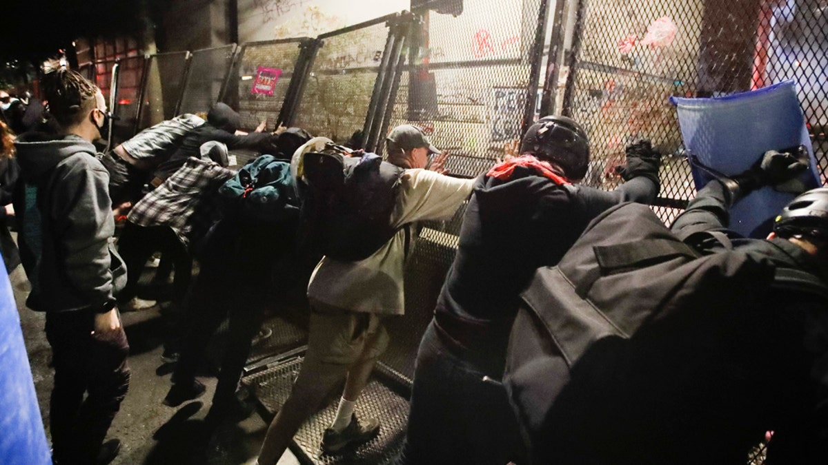 Demonstrators try to topple a steel fence during a Black Lives Matter protest at the Mark O. Hatfield United States Courthouse Saturday, July 25, 2020, in Portland, Ore. (AP Photo/Marcio Jose Sanchez)