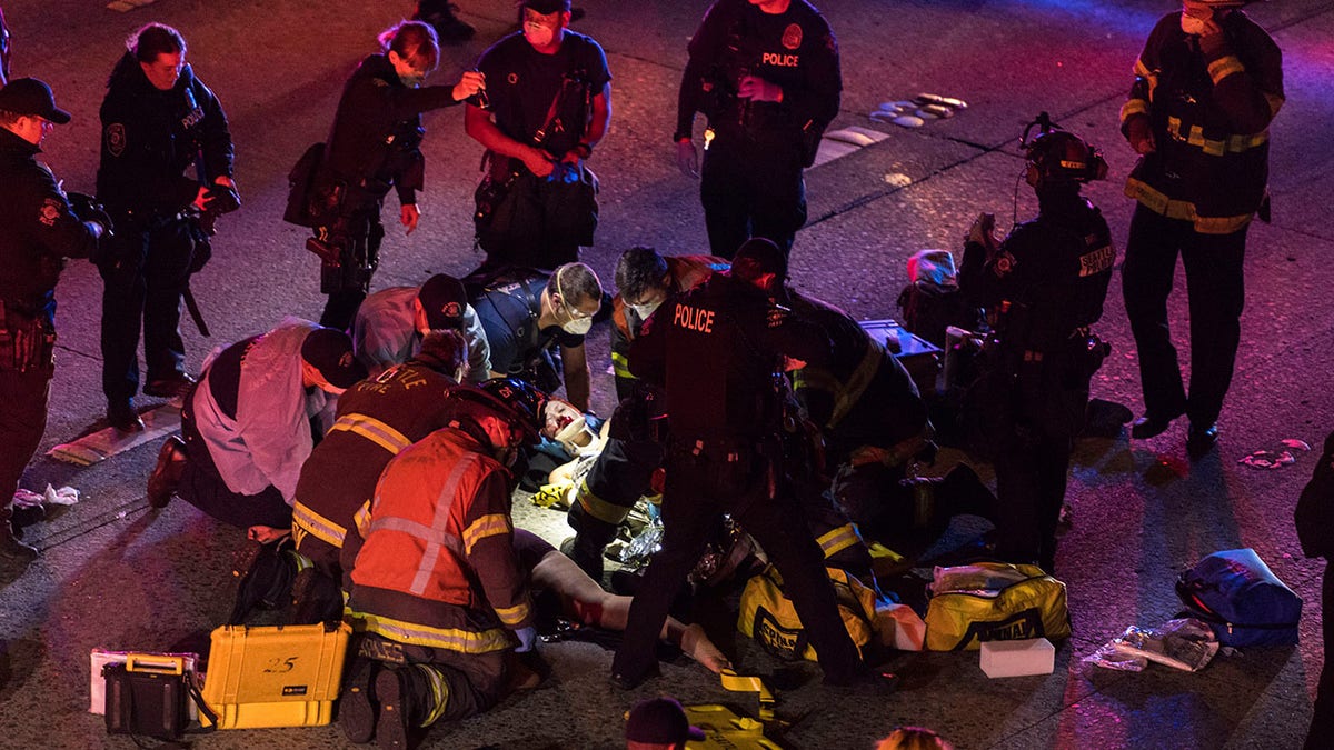 Emergency workers tend to an injured person on the ground after a driver sped through a protest-related closure on the Interstate 5 freeway in Seattle, authorities said early Saturday, July 4, 2020. (James Anderson via AP)