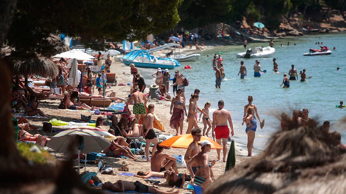 Sunbathers enjoy the beach in Pollença, in the Balearic Island of Mallorca, Spain on Tuesday. The U.K. government's recommendation against all but essential travel to the whole of Spain means that all travelers arriving in Britain from that country will have to undergo a 14-day quarantine. (AP Photo/Joan Mateu)