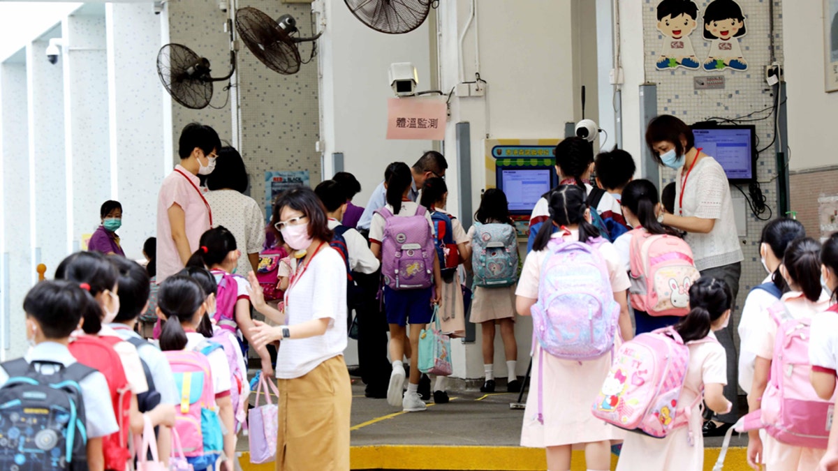 Students wearing face masks wait in line to have body temperatures checked at the entrance of a school on June 15, 2020, in Hong Kong, China. (Hong Fan/China News Service via Getty Images)