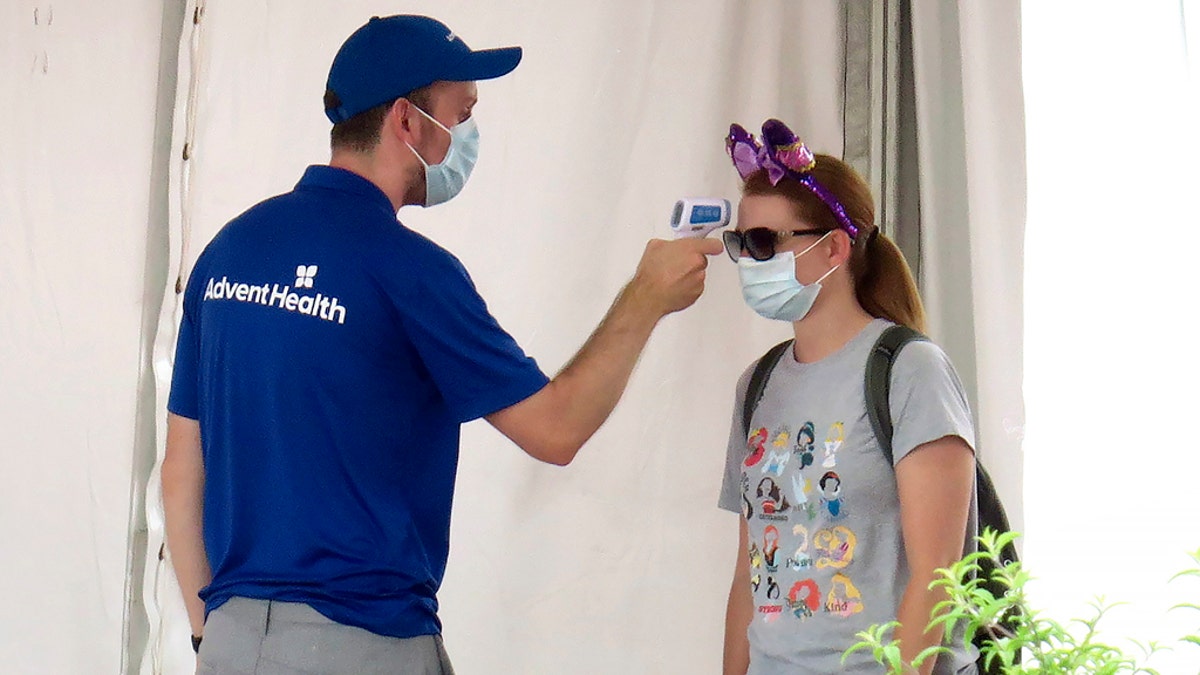 A guests gets her temperature taken before entering the official reopening day of the Magic Kingdom at Walt Disney World in Lake Buena Vista, Fla., July 11. Disney reopened two Florida parks, the Magic Kingdom and Animal Kingdom, Saturday with limited capacity and safety protocols in place. (Joe Burbank/Orlando Sentinel via AP)