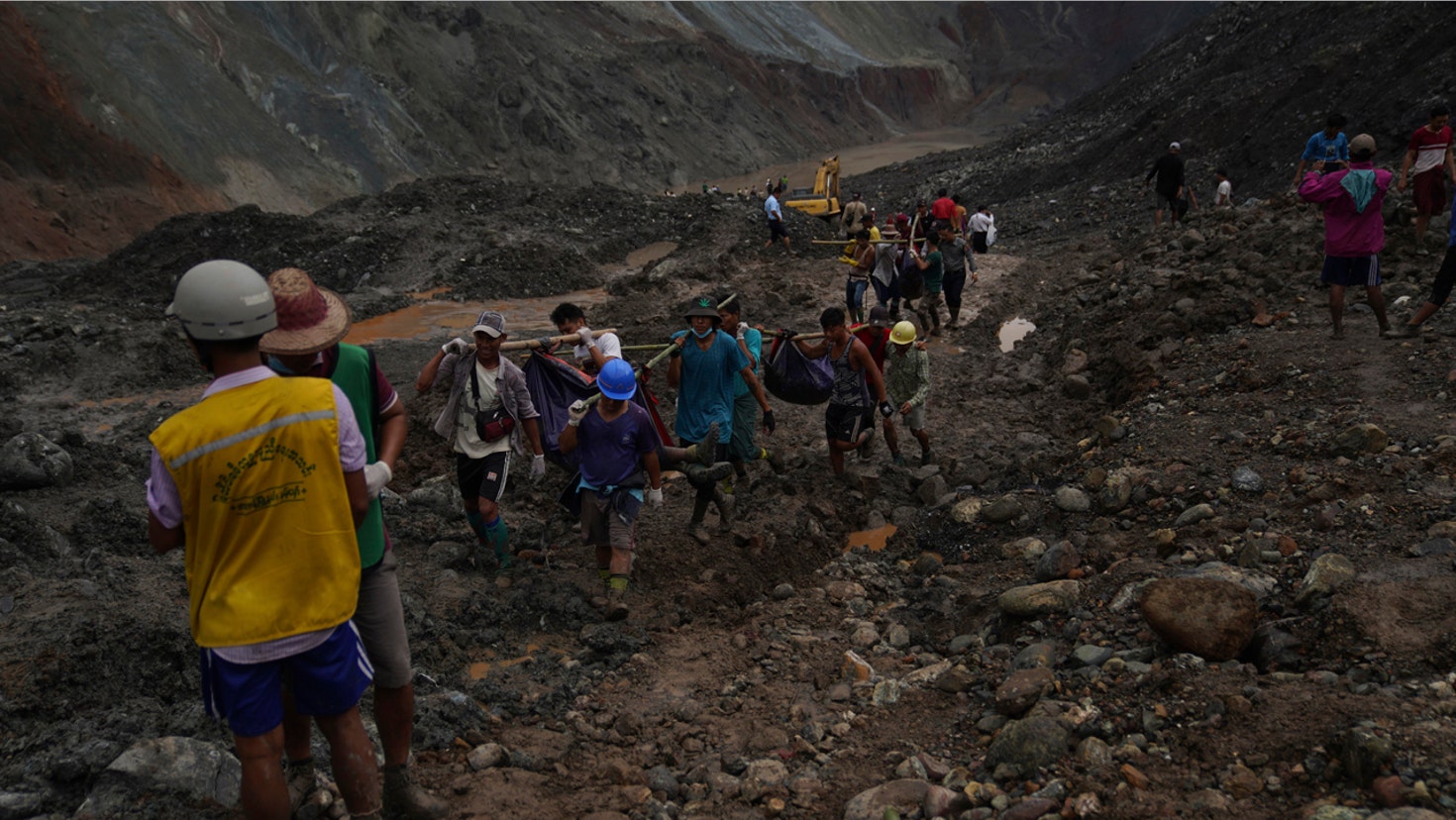 Rescue workers use poles to carry bodies shrouded in blue and red plastic sheets July 2, in Hpakant, Kachin State, Myanmar.