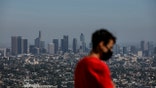 Izzy Galvan, 20, wears a face mask while visiting the Griffith Observatory overlooking downtown Los Angeles, Wednesday, July 15, 2020, in Los Angeles. Coronavirus cases have surged to record levels in the Los Angeles area, putting the nation's largest county in "an alarming and dangerous phase" that if not reversed could overwhelm intensive care units and usher in more sweeping closures, health officials said Wednesday. (AP Photo/Jae C. Hong)