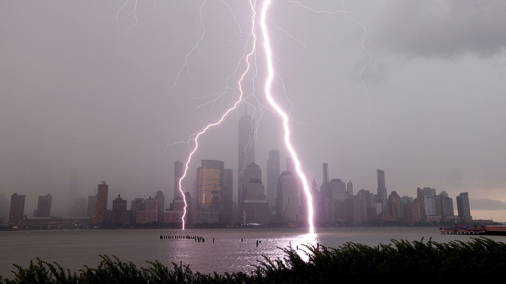 Two lightning bolts frame One World Trade Center as they hit the Hudson River in front of the skyline of lower Manhattan during a thunderstorm in New York City, July 6, 2020.