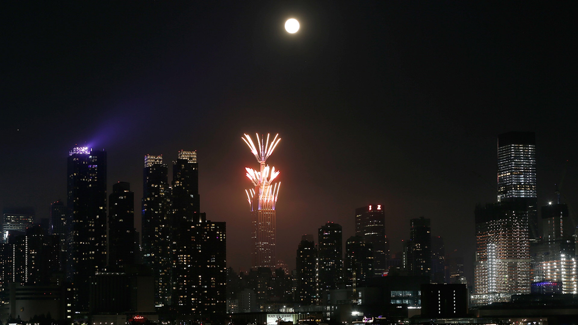 Macy's fireworks go off on the top of the Empire State Building as the full buck moon rises in the sky in New York City, July 4, 2020.