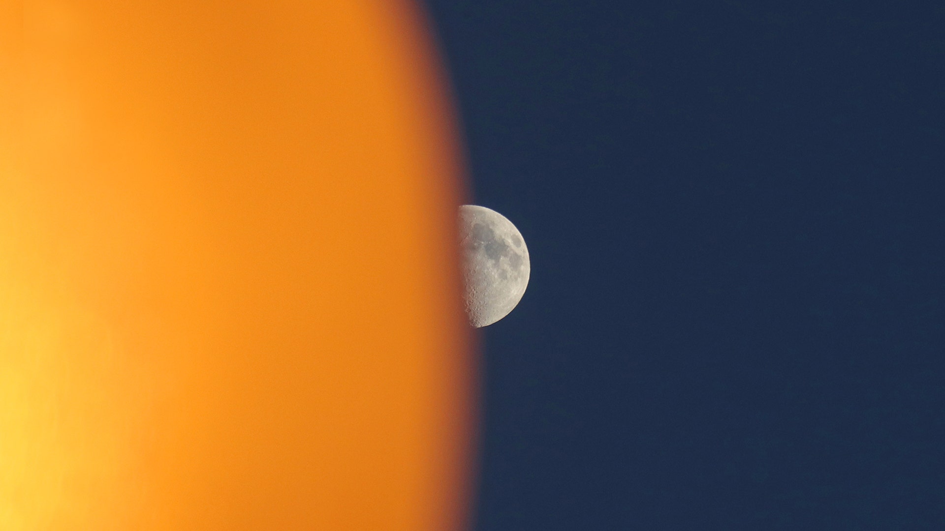 The moon rises behind a street lamp in Weehawken, New Jersey, June 28, 2020. 