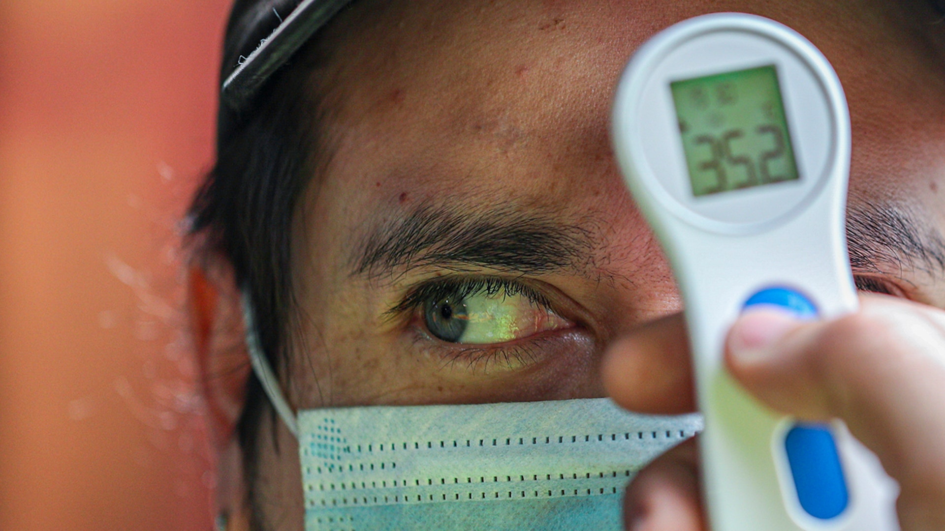 A worker measures the temperature of a man before allowing him to enter the La Vega market in Santiago, Chile, July 19, 2020. 