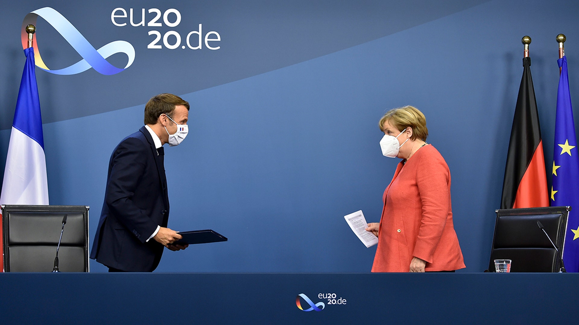 German Chancellor Angela Merkel and French President Emmanuel Macron prepare to address a media conference at the end of an EU summit in Brussels, July 21, 2020. 