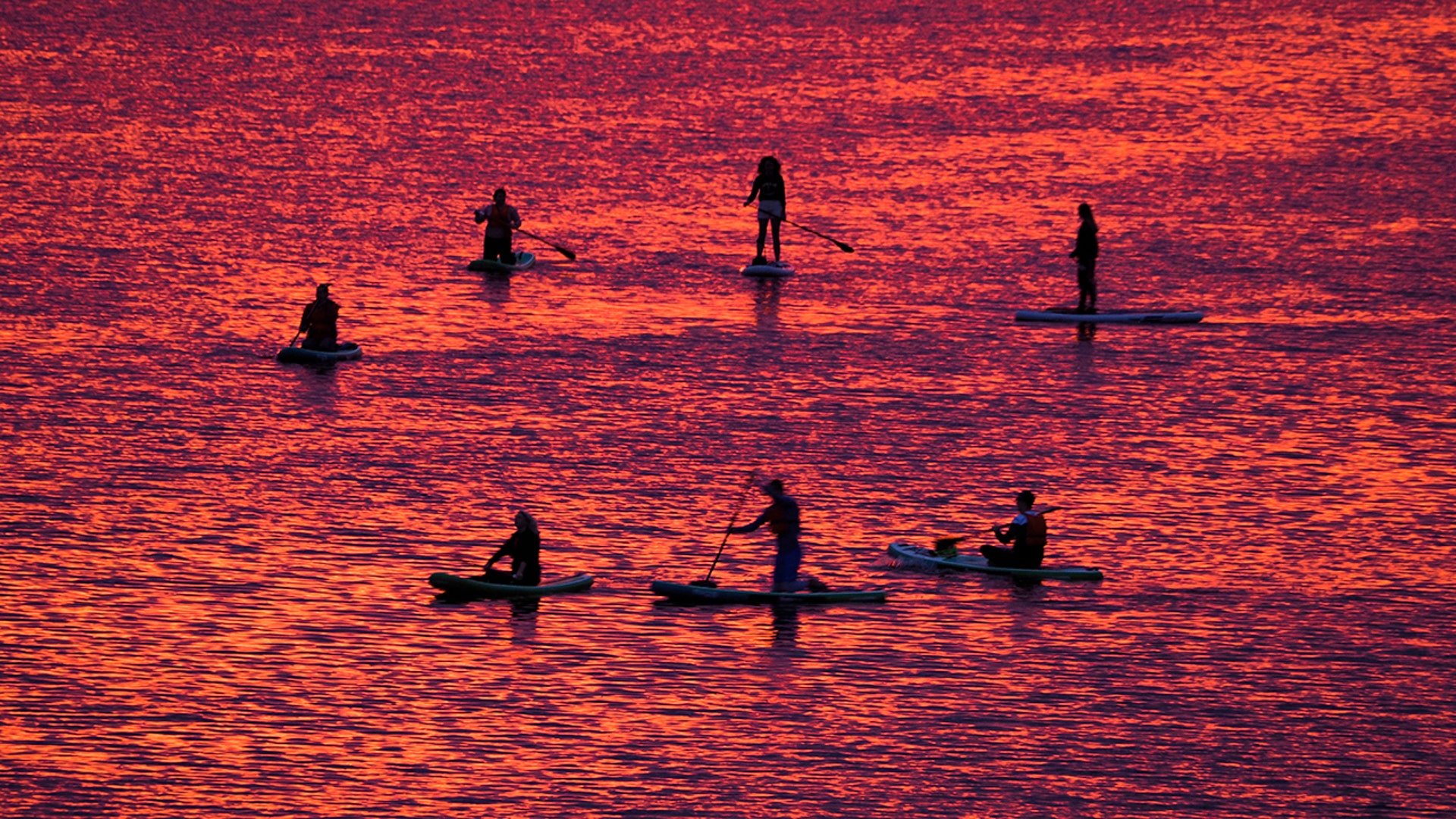 People steer their paddleboards at sunset on the Velikaya River in Pskov, Russia, July 6, 2020. 