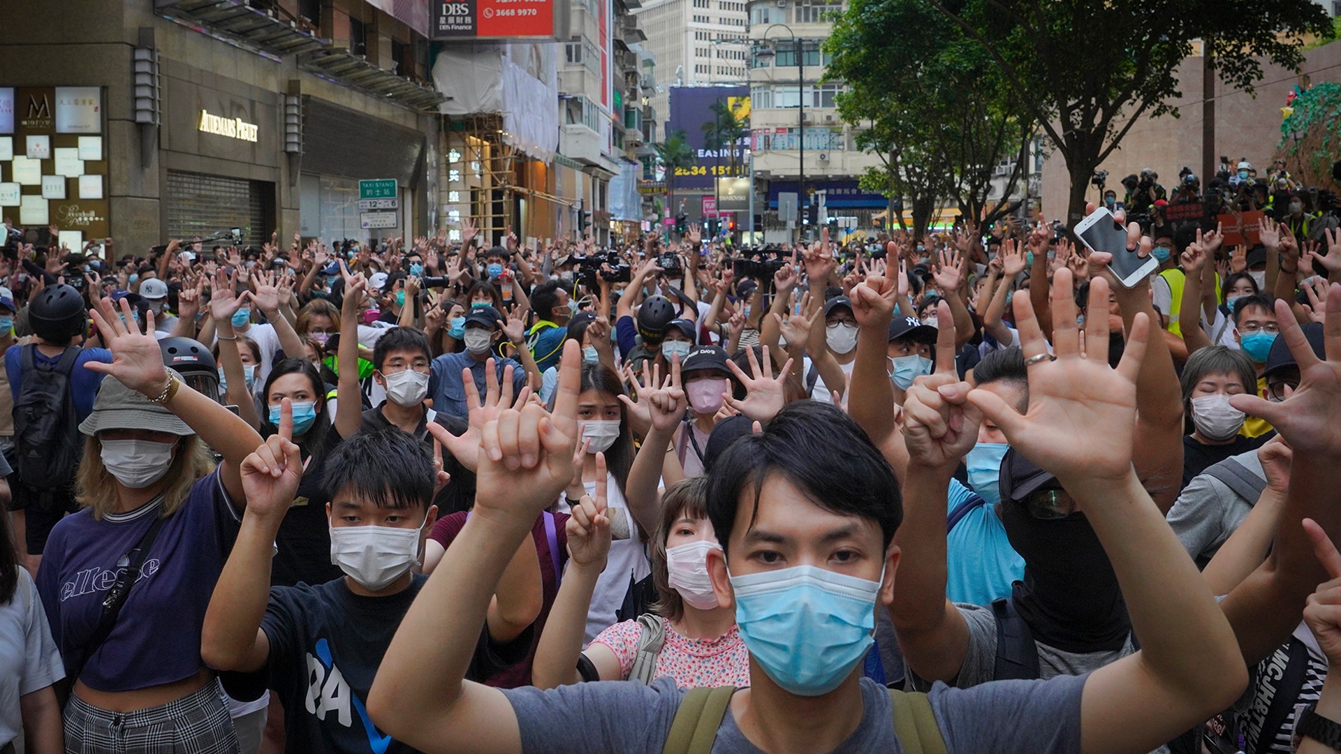 Protesters against the new national security law gesture with five fingers, signifying the "Five demands - not one less" on the anniversary of Hong Kong's handover to China from Britain in Hong Kong, July. 1, 2020. 