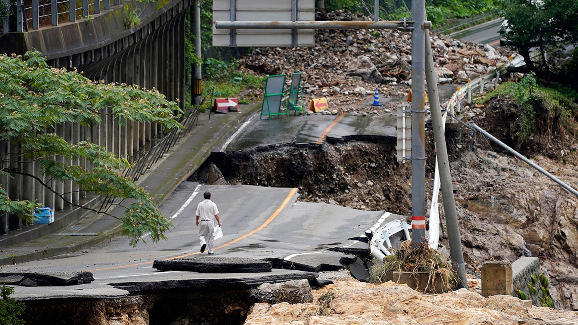 A man walks on a damaged road following heavy rain in Kumamura, Japan, July 6, 2020. 