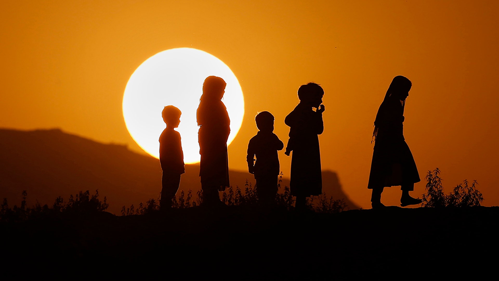 Children are silhouetted against the sunset while playing on a hilltop on the outskirts of Islamabad, Pakistan, July 5, 2020.