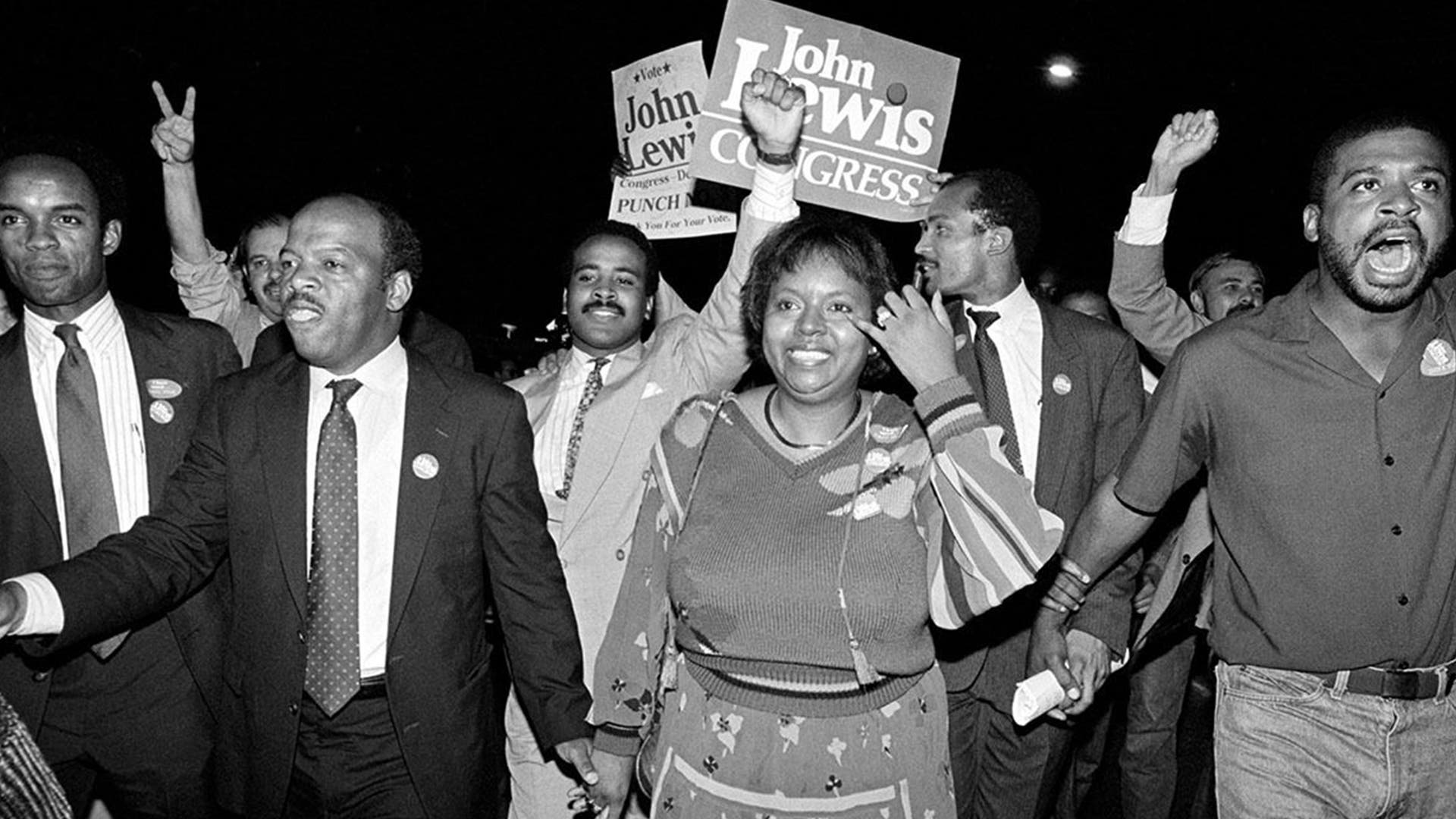 John Lewis, front left, and his wife, Lillian, holding hands, lead a march of supporters from his campaign headquarters to an Atlanta hotel for a victory party after he defeated Julian Bond in a runoff election for Georgia's 5th Congressional District seat in Atlanta, Sept. 3, 1986.