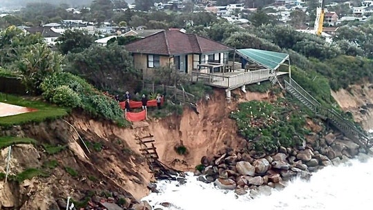 Australian homes teetering on cliff as waves lash coastline