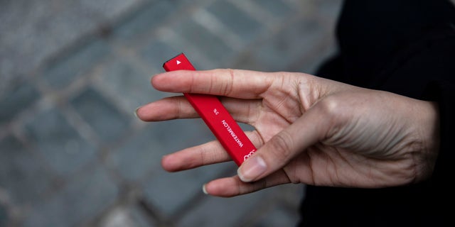 In this Jan. 31, 2020 file photo a woman holds a Puff Bar flavored disposable vape device in New York. U.S. health officials are cracking down on the brand of fruity disposable e-cigarettes that is popular with teenagers, saying the company never had permission to launch in the U.S. The Food and Drug Administration sent a letter Monday, July 20 telling the maker of Puff Bar e-cigarettes to remove its products from the market, including flavors like Mango, Pink Lemonade and Strawberry. 