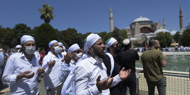 Muslims pray during Friday prayers at the historic Sultanahmet district of Istanbul, near the Byzantine-era Hagia Sophia, background, Friday, July 24, 2020.