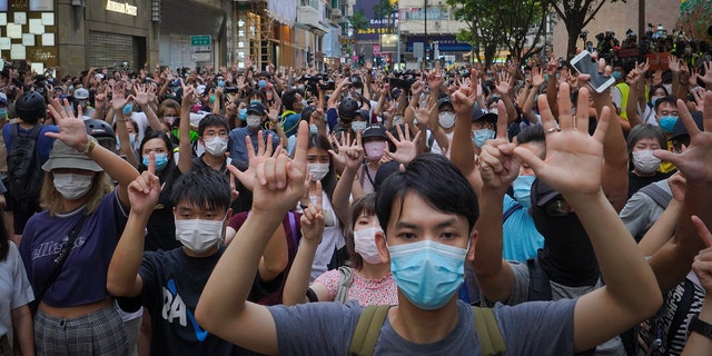 Protesters against the new national security law gesture with five fingers, signifying the "Five demands - not one less" on the anniversary of Hong Kong's handover to China from Britain in Hong Kong, Wednesday, July. 1, 2020. (AP Photo/Vincent Yu)