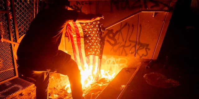 A Black Lives Matter protester burns an American flag outside the Mark O. Hatfield U.S. Courthouse on July 20, 2020 in Portland, Oregon.