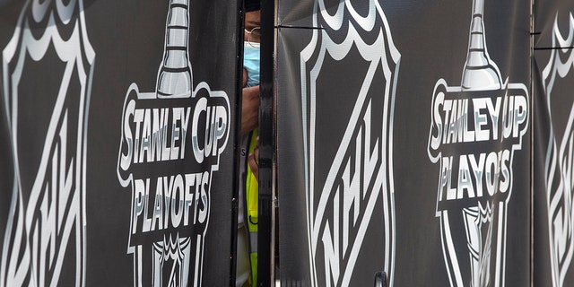 A security guard peers out from behind NHL-branded fencing at the entrance where players arrive at Toronto's Royal York hotel, which is acting as the 