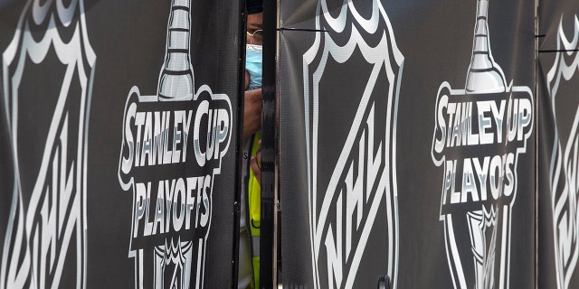 A security guard peers out from behind NHL-branded fencing at the entrance where players arrive at Toronto's Royal York hotel, which is acting as the