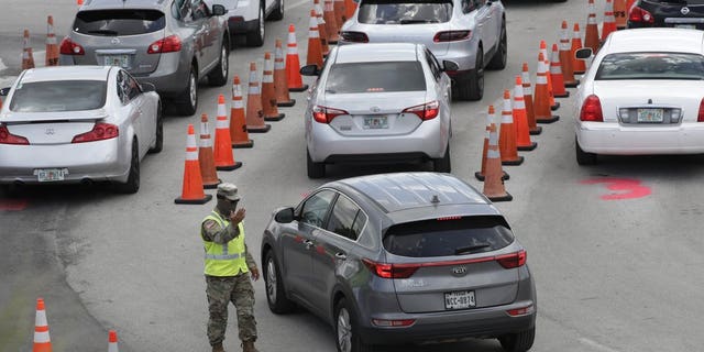 A National Guardsman directs traffic at a COVID-19 testing site outside Hard Rock Stadium, Wednesday, July 8, 2020, in Miami Gardens, Fla. Florida is one of the nation's hot spots for coronavirus.