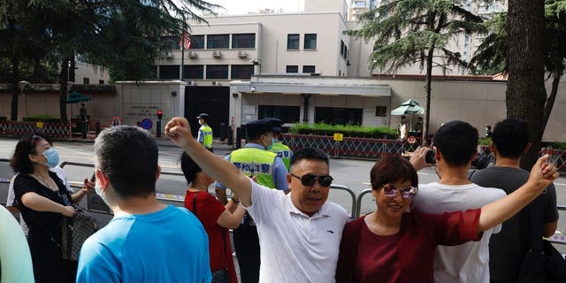 Residents raise their fists to pose for a photo outside the United States Consulate in Chengdu in southwest China's Sichuan province on Sunday, July 26, 2020. China ordered the United States on Friday to close its consulate in the western city of Chengdu, ratcheting up a diplomatic conflict at a time when relations have sunk to their lowest level in decades.