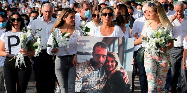 Veronique Monguillot, wife of Philippe Monguillot, a bus driver who was attacked in Bayonne on Sunday night, holding a photo of her with her husband, during a protest march in Bayonne, southwestern France. (AP Photo/Bob Edme)