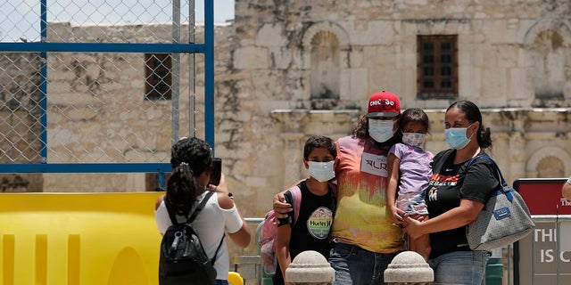Visitors wearing masks to protect against the spread of COVID-19 pose for photos at the Alamo, which remains closed, in San Antonio last month. Cases of COVID-19 have spiked in Texas to over 200,000, according to government figures. (AP Photo/Eric Gay)